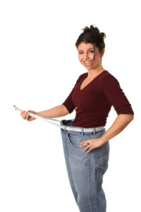 Pretty brunette showing with a measuring tape around her waist how much centimeters she has already lost